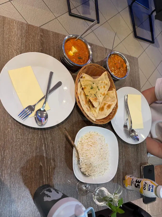 Ein gedeckter Tisch von oben mit Curry, Naan und Reis